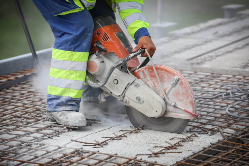 Worker is cutting concrete with circular saw for concrete, detail of the construction scene.